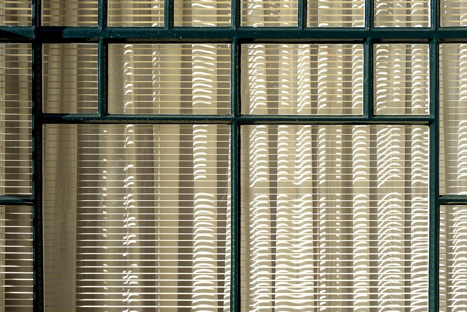 Aesthetic window with blinds and shadows creating an intricate pattern.